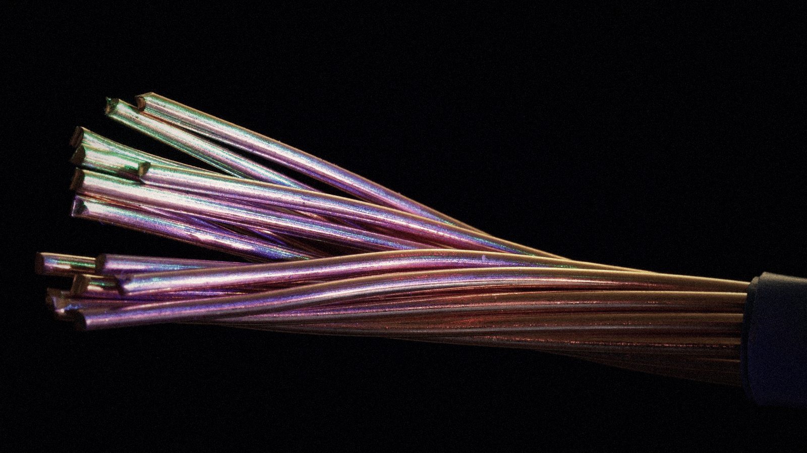 Haz de cables iridiscentes que convergen en un solo punto, sobre fondo negro