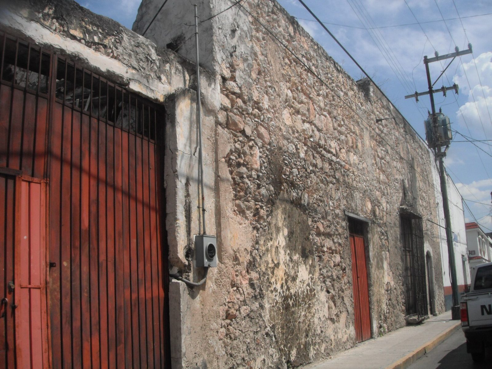 Fachada de piedra con puerta de madera roja.